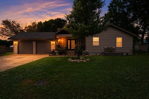 A residential house with a garage, a front porch, and a well-maintained lawn.