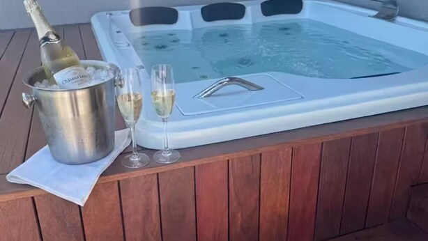 A hot tub with champagne and glasses on a wooden deck. - Duplex Penthouse with Jacuzzi and Views of 2 Beaches (Bombinhas)