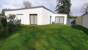 Een modern huis met een plat dak, een garage en een verzorgd gazon.