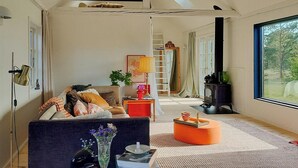 A living room with a sofa, a coffee table, a ladder, a fireplace, and a large window. - Converted 1800s stable near Kalmarsund (Söderåkra)