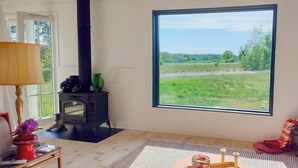 A room with a large window, a fireplace, a rug, and a blanket. - Converted 1800s stable near Kalmarsund (Söderåkra)