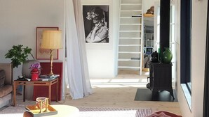 A modern living room with a sofa, a coffee table, a rug, and a view of a staircase leading to a loft. - Converted 1800s stable near Kalmarsund (Söderåkra)