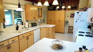 Eine Küche mit Holzschränken, einer Marmorarbeitsplatte, einem Einbauofen und einem Kühlschrank.