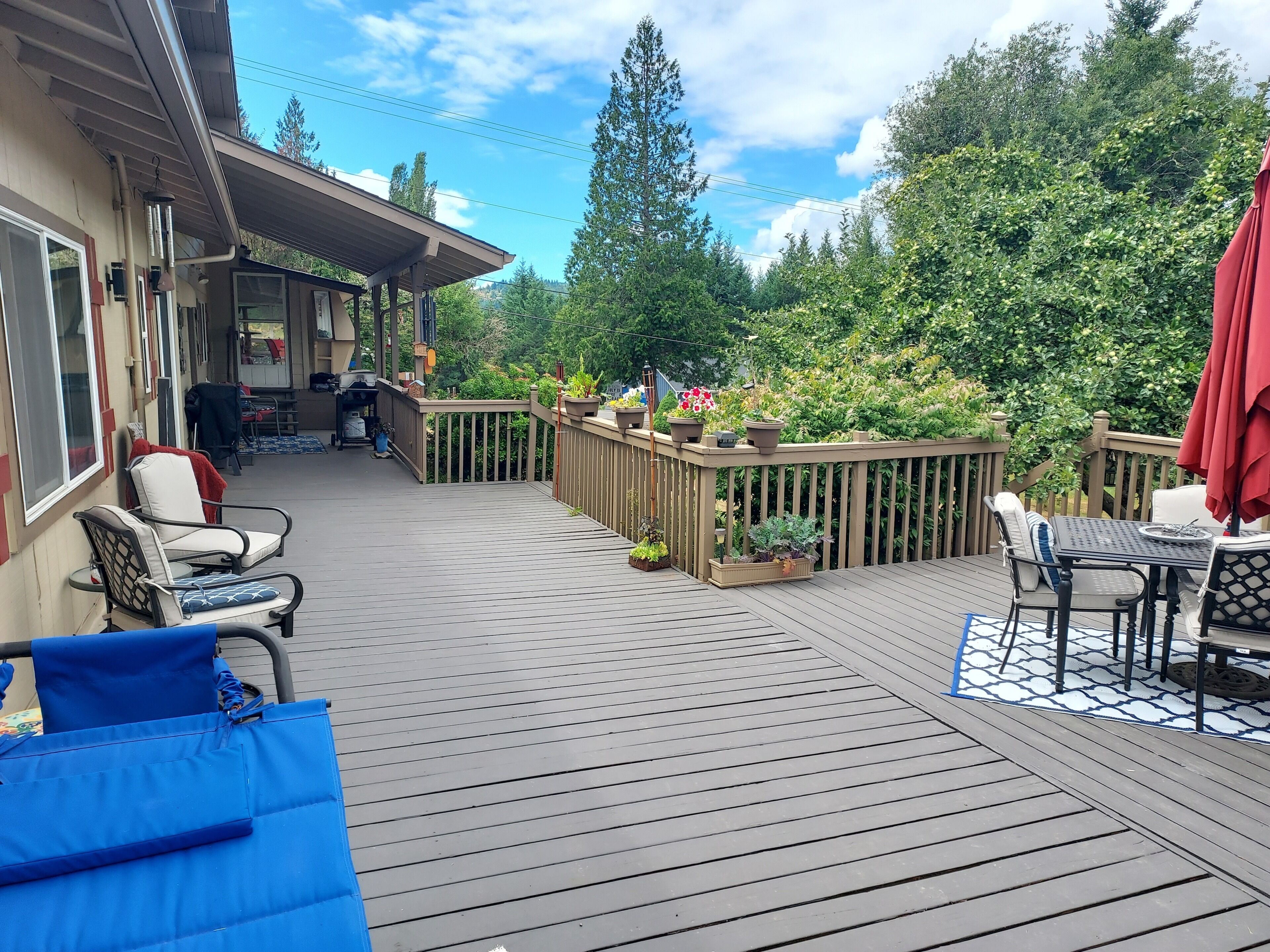 A deck with outdoor furniture, a covered area, and a view of the surrounding greenery.