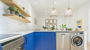 Eine moderne Küche mit blauen Schränken, Edelstahlgeräten und Pendelleuchten.