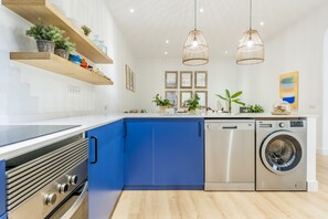 Eine moderne Küche mit blauen Schränken, Edelstahlgeräten und Pendelleuchten.