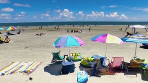 Una playa con sombrillas coloridas, sillas de playa y juguetes inflables.