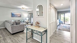 Una sala de estar con un sofá gris, una mesita con una lámpara, una escultura decorativa de pez y un espejo grande en la pared.