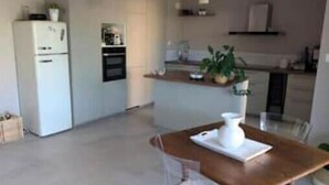 Una cocina moderna con una isla central, un refrigerador y un comedor con mesa y sillas.
