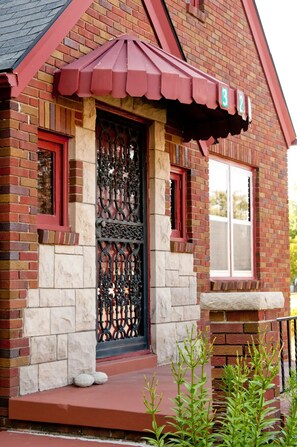 A brick house with a red door, a stone base, and a small porch. - Walnut Row, Walk to Valley Junction,  Sleeps 10+ (West Des Moines)