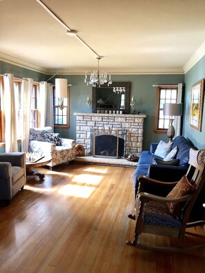 A living room with a fireplace, a chandelier, and a blue sofa. - Walnut Row, Walk to Valley Junction,  Sleeps 10+ (West Des Moines)