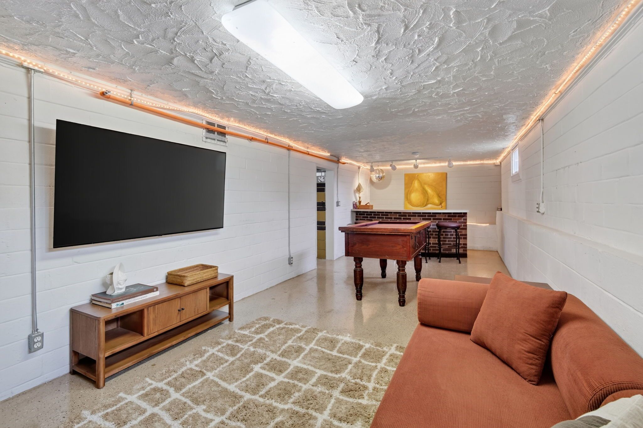 Una sala de estar moderna con un televisor de pantalla plana, muebles de madera, una mesa de centro y un sofá.