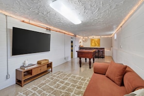 A modern living room with a flat-screen TV, wooden furniture, a coffee table, and a sofa. - Walnut Row, Walk to Valley Junction,  Sleeps 10+ (West Des Moines)