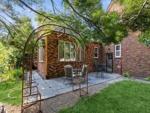A patio with a swing set, a brick building, and a door.