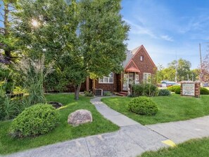 A brick house with a red roof, a front yard with a pathway, and a sign indicating the property name. - Walnut Row, Walk to Valley Junction,  Sleeps 10+ (West Des Moines)