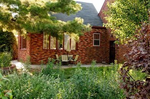 A brick house with a patio, outdoor seating, and a garden. - Walnut Row, Walk to Valley Junction,  Sleeps 10+ (West Des Moines)