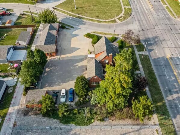 An aerial view of a residential area with houses, a parking lot, and a road. - Walnut Row, Walk to Valley Junction,  Sleeps 10+ (West Des Moines)