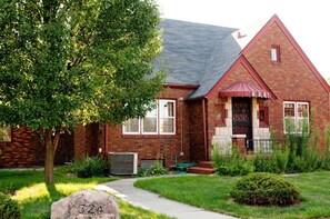 A brick house with a red roof, a front porch, and a number '324' on the front steps. - Walnut Row, Walk to Valley Junction,  Sleeps 10+ (West Des Moines)