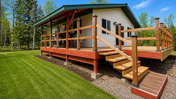 Eine Hütte mit überdachter Veranda, einer Holzterrasse und einer Treppe zum Eingang.