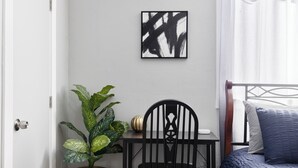 Une pièce comprenant un lit, un bureau, une chaise, une plante en pot et une œuvre d’art murale.