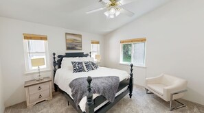 A bedroom with a bed, bedside tables, a chair, a ceiling fan, and windows. - Amazing Ocean view 1 mile to Brookings! (Brookings)