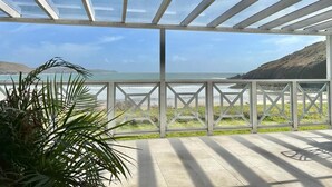 Ein überdachter Außenbereich mit Blick auf das Meer und die Hügel.