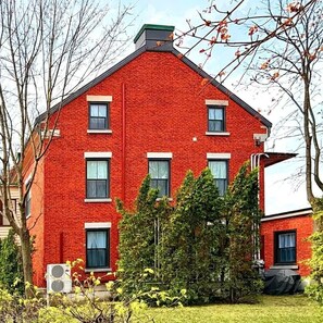 A red brick building with multiple windows and a green roof. - Les Ancestrales - Maison Turcot Art Déco (Saint-Hyacinthe)