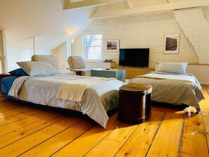 A loft-style bedroom with two beds, a television, and a window. - Les Ancestrales - Maison Turcot Art Déco (Saint-Hyacinthe)
