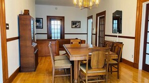 A dining area with a wooden table and chairs, a chandelier, and wooden paneling on the walls. - Les Ancestrales - Maison Turcot Art Déco (Saint-Hyacinthe)