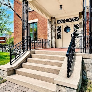 A building entrance with a brick facade, a stone wall, and a metal gate.