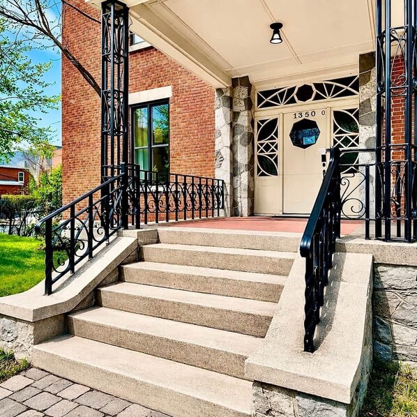 A building entrance with a brick facade, a stone wall, and a metal gate.