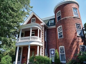 A two-story brick building with a balcony and a tower-like structure. - Les Ancestrales - Suite romantique (Saint-Hyacinthe)