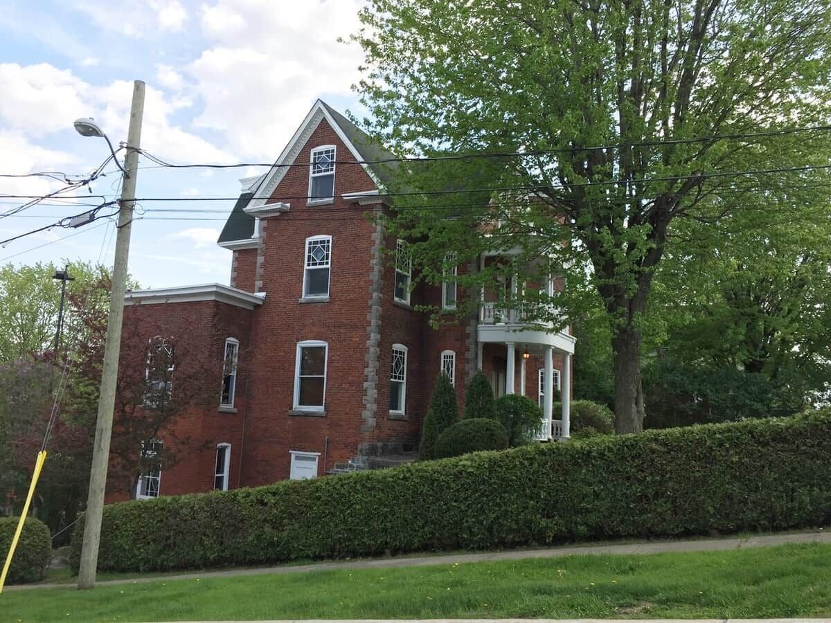 A large, red brick building with a prominent front porch and a symmetrical facade.
