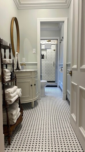 A bathroom with white tiled walls, a white sink, and a shower area.