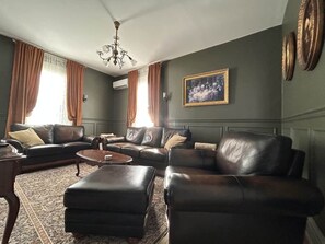 Una sala de estar con sofás de cuero, una mesa de centro y una araña.