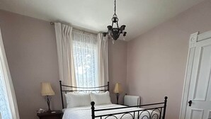 Une chambre à coucher avec un lit à baldaquin, deux tables de chevet avec des lampes, un radiateur et un plancher en bois.