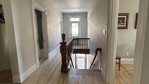 Un hall d’entrée spacieux, doté d’un plancher en bois, d’un ventilateur de plafond et d’un escalier menant à un autre niveau.