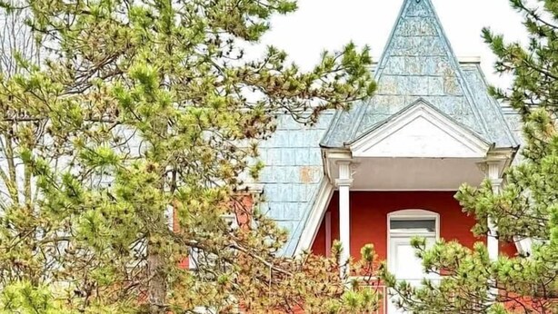 Un bâtiment rouge avec un toit à pignon et une entrée principale.