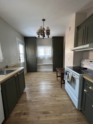 Una cocina con candelabro, suelo de madera y armarios oscuros.