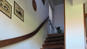 A wooden staircase with a handrail, a landing with a plant, and two framed pictures on the wall. - Vacation apartment in Emsland (Papenburg)