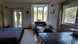 Une pièce comprenant un lit, un canapé, une table et donnant sur l’extérieur.