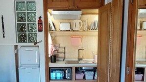 Une cuisine de taille réduite, avec des meubles de rangement en bois, un évier encastré et un réfrigérateur.