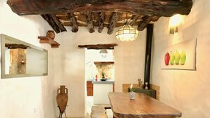 A rustic interior with a wooden dining table, benches, a hanging light fixture, and a wall-mounted mirror. - Villa 'Sa Paissa De Can Sergent' with Mountain Views, Wi-Fi, and Air Conditioning (Cala Vedella)