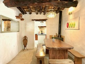 A rustic interior with a wooden dining table, benches, a hanging light fixture, and a wall-mounted mirror.