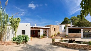 A traditional Mediterranean-style villa with a stone courtyard, white walls, and potted plants. - Villa 'Sa Paissa De Can Sergent' with Mountain Views, Wi-Fi, and Air Conditioning (Cala Vedella)