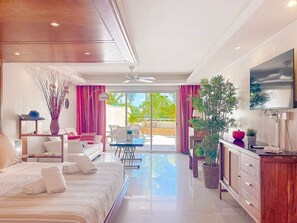 Ein modernes Hotelzimmer mit Bett, Sofa, Esstisch und Fernseher.