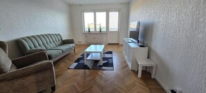 Un salon comprenant un canapé, une table basse, un meuble pour la télévision et une fenêtre donnant sur un beau paysage.