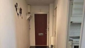 A hallway with a dark floor, a light-colored wall, and a door at the end. - Cozy apartment near Volvo Cars (Gothenburg)