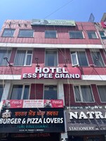 Un edificio de varios pisos con un letrero llamativo que indica 'Hotel Ess Pee Grand', mostrando habitaciones con aire acondicionado las 24 horas del día, los 7 días de la semana.