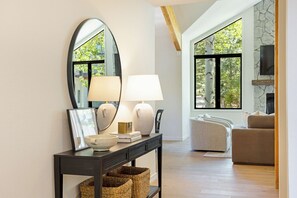A modern living room with a fireplace, a large window, and a console table with decorative items. - NEWLY ADDED! 6 BR Mountain & Golf retreat, Hot tub, Newly remodeled & furnished (Avon)